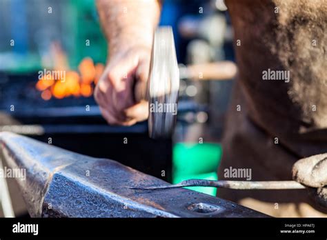 Blacksmith Hammering Hot Iron Rod On Anvil Against The Background Of Fire Stock Photo Alamy