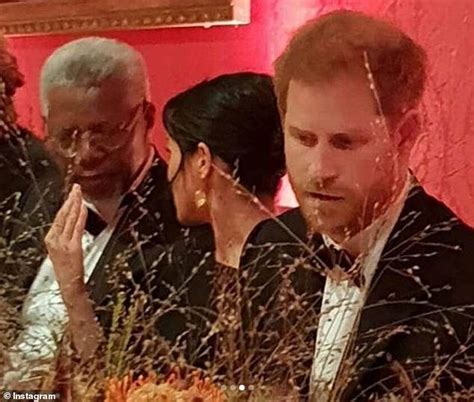 Two Men In Tuxedos Are Looking At A Cake With Candles On It And One Man