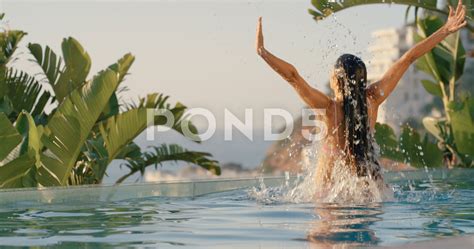 Beautiful Woman Jumping Out Of Swimming Pool Water With Arms Raised