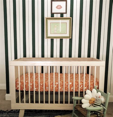 Nursery With Green Striped Wall And Feminine Details