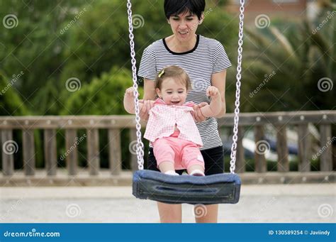 Mother Swinging Her Little Daughter On A Swing Stock Photo Image Of