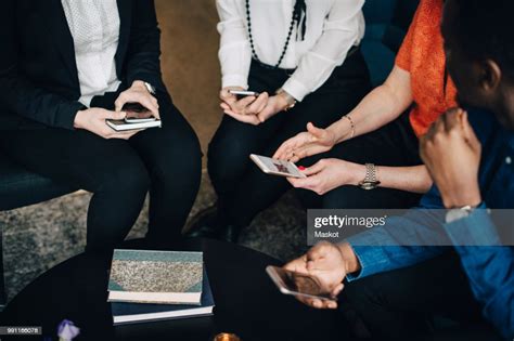 Low Section Of Business People Using Mobile Phones While Sitting At