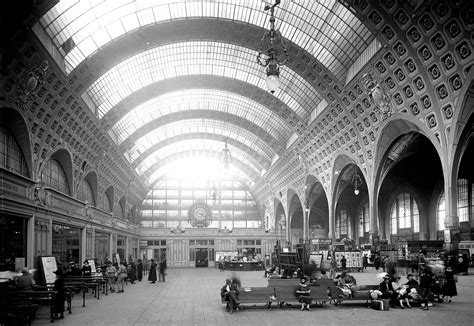 The Interior Of An Old Train Station With People Sitting On Benches And