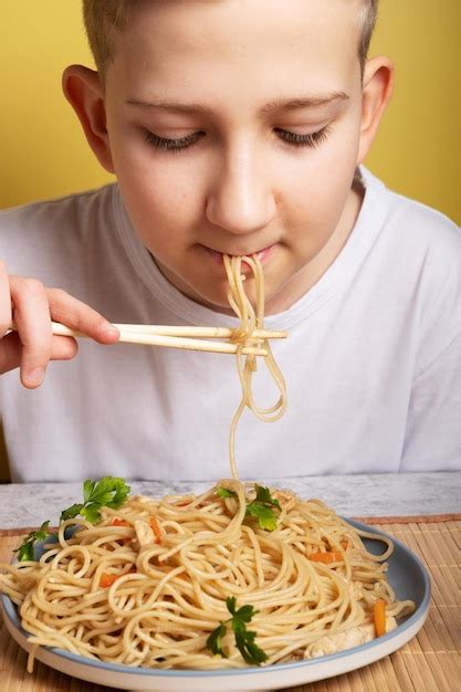 El niño come fideos con palillos en japonés con pollo retrato de primer