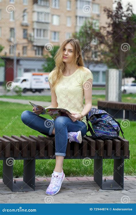 Young Beautiful Girl Sitting On A Bench In The Summer Park Stock Photo