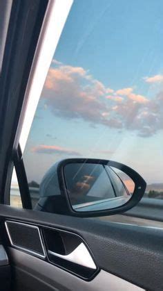 The Side View Mirror Of A Car As It Drives Down A Highway With Clouds