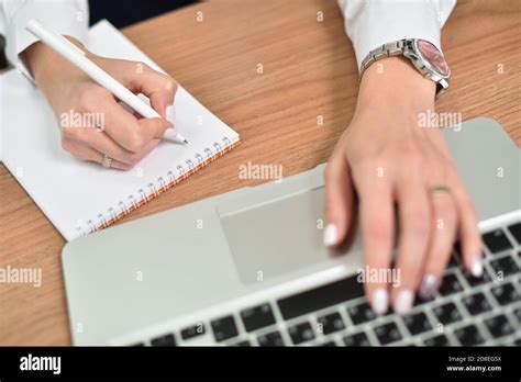 Close Up Of Female Hands Writing In Notepad And Typing On Laptop