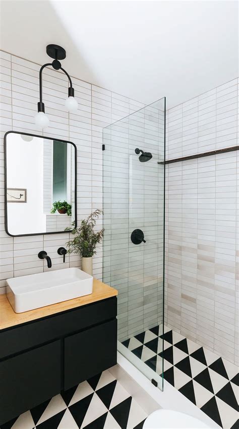 A Black And White Tiled Bathroom With A Sink Mirror And Standup Shower