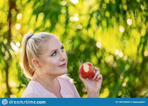 Blonde Woman Eats Healthy Red Apple In Garden Stock Photo Image Of Beauty Garden 139130204