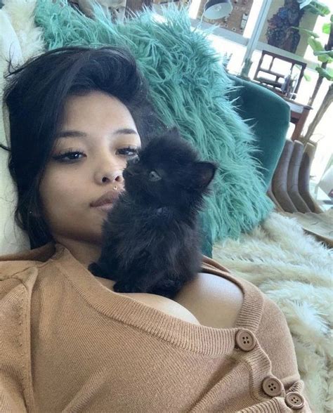 A Woman Laying On Top Of A Couch Holding A Black Cat