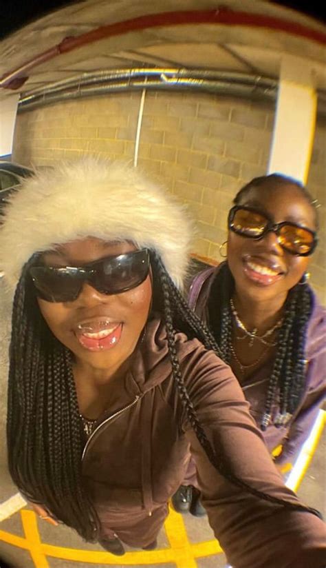 Two Women Are Taking A Selfie In Front Of A Brick Wall And Wearing