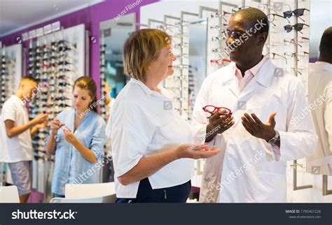 Professional Male Optician Helping Mature Woman Stock Photo 1795401226