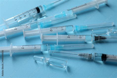 Disposable Syringes With Needles And Ampules On Light Blue Background