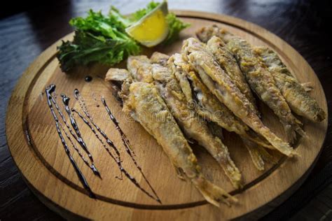 Fried Red Mullet Fish On A Wooden Plate With Lemon And Salad Stock