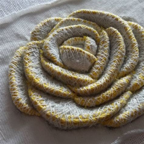 A Close Up Of A Cloth Flower On A White Tablecloth With Yellow And Gray