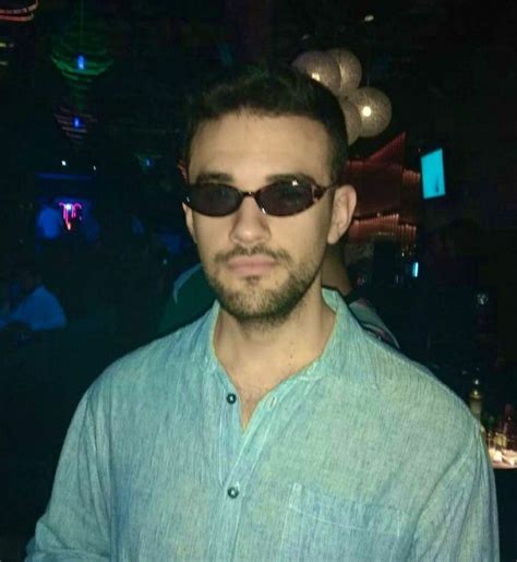 A Man Wearing Sunglasses Standing In A Dark Room