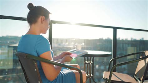 Mujer Sentado En El Balcón Y Leyendo Un Libro A Puesta De Sol 23824726 Vídeo De Stock En Vecteezy