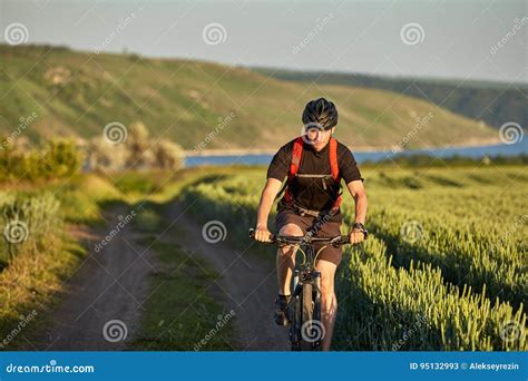 Young Cyclist Rides Mountain Bicyclist On The Road In The Field In The