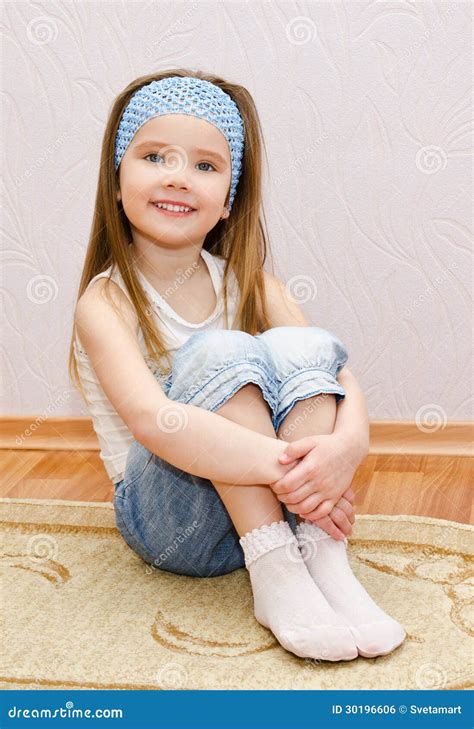 Petite Fille De Sourire S Asseyant Sur Un Plancher De Maison Photo