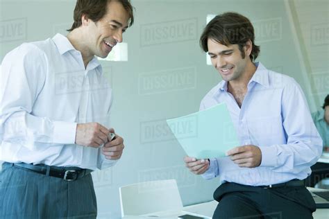 Two Businessmen Looking At Document Smiling Stock Photo Dissolve