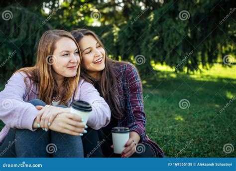 Attractive Lesbian Couple Drinking Coffee On Grass In Park With Copy Space Girls Sit Close To