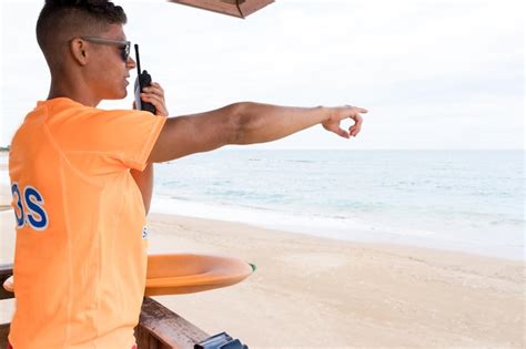 Premium Photo Lifeguard Using Radio And Pointing To The Horizon