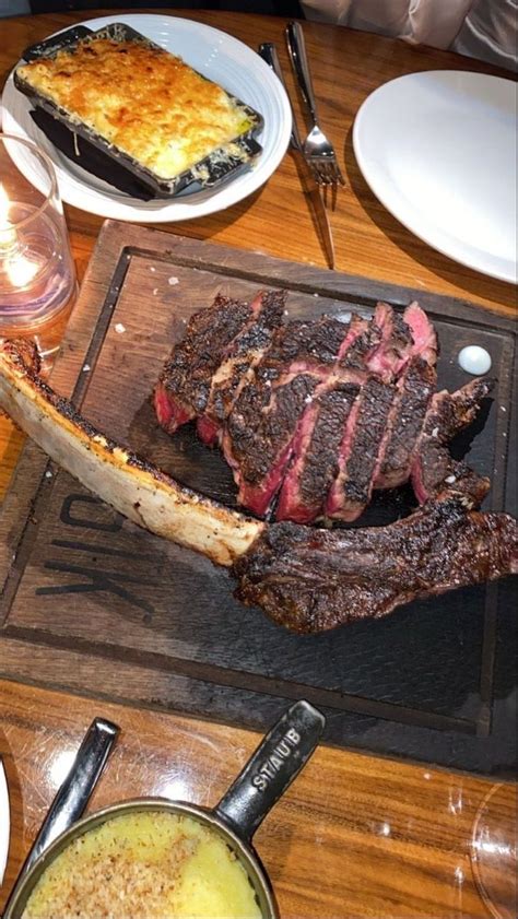 The Steak Is Ready To Be Served On The Table With Other Plates And Utensils