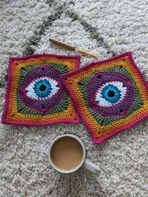 Two Crocheted Coasters With An Eye On Them And A Cup Of Coffee