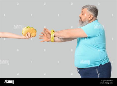 Overweight Mature Man Hands Tied With Measuring Tape On Grey Background