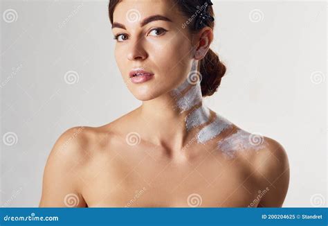 Naked Woman With Paint On Neck Is In The Studio Against White