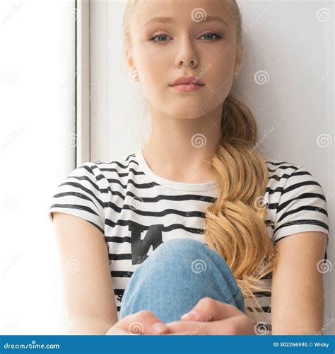 Pretty Teenaged Blonde Sitting On A Window Sill Portrait Stock Photo