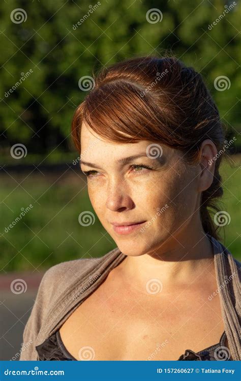 Portrait Of Beautiful Serious Middle Aged Woman With Calm Face Looking Aside In Summer Green