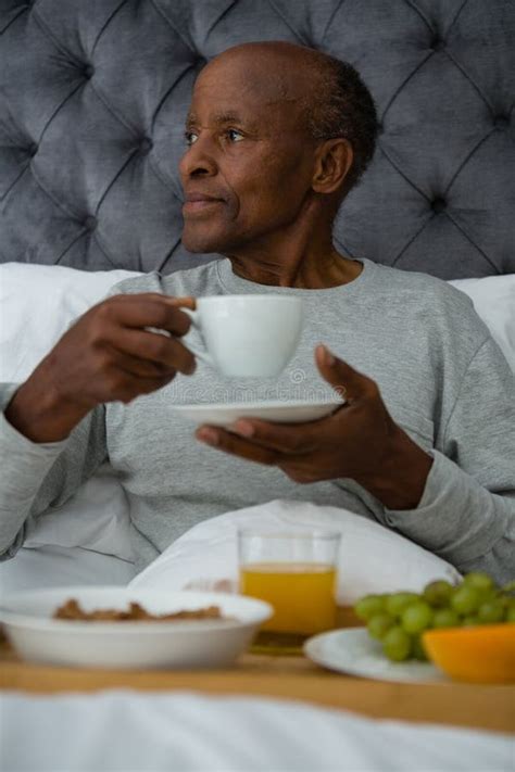 Thoughtful Senior Man Looking Away While Having Breakfast On Bed Stock