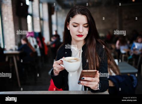 Brunette Girl Sitting On Cafe With Cup Of Cappuccino And Looking At