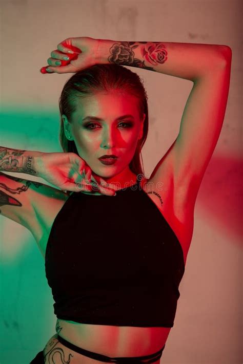 Blonde In Black Underwear Adjusts The Strap Of Her Bra While Lying On A Black Leather Sofa Stock