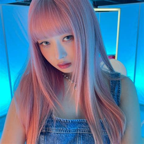 a girl with pink hair and blue overalls posing for a photo in front of ...