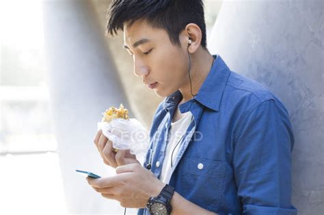 Chinese man eating food and using smartphone — music, male - Stock ...