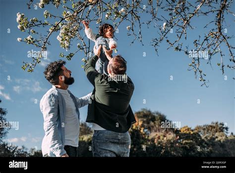 Un Couple Gay Masculin Levant Leur Jeune Fille Pour Toucher Les Fleurs D Un Arbre Concept De