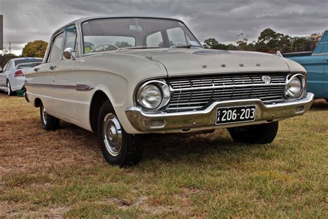 An Old Car Is Parked On The Grass In Front Of Other Classic Cars And Trucks