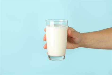 Premium Photo Female Hand Hold Glass Of Milk On Blue Background