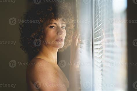 Charming Naked Woman Near Window Looking At Camera Stock Photo