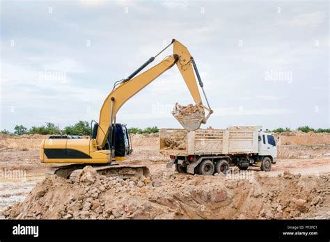 Yellow Excavator Machine Loading Soil Into A Dump Truck At Construction