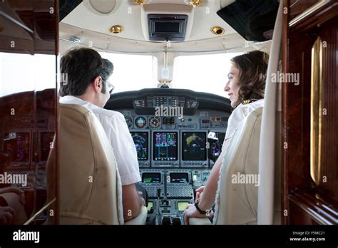 Rear view of male and female pilots talking in cockpit of private jet Stock Photo - Alamy