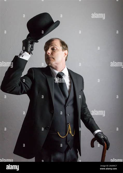 Portrait Of British Butler In Dark Suit Politely Doffing Bowler Hat