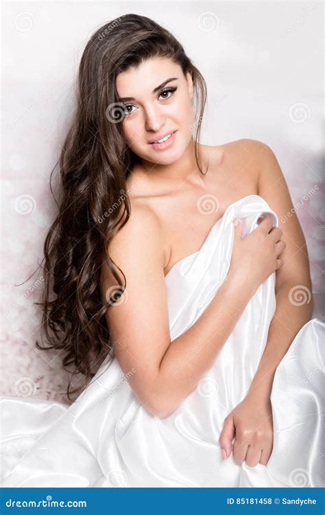 Pretty Female In Peignoir Sleeping On Bed Under Silk Sheets Stock Photo