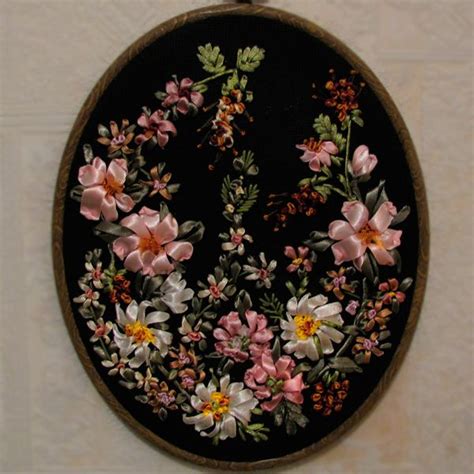 An Embroidered Wall Hanging With Pink Flowers On Black Fabric And Gold