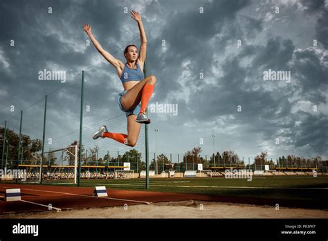 Female Athlete Performing A Long Jump During A Competition At Stadium