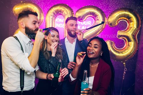 Multiracial People With Party Trumpets And Drinks Celebrating New Years