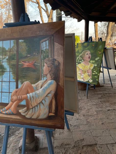 Some Paintings Are On Easels Outside By The Water