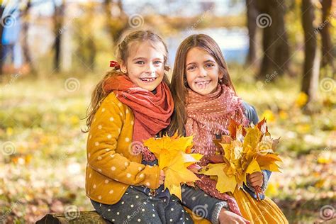 Two Cute Smiling 8 Years Old Girls Posing Together In A Park On A Sunny